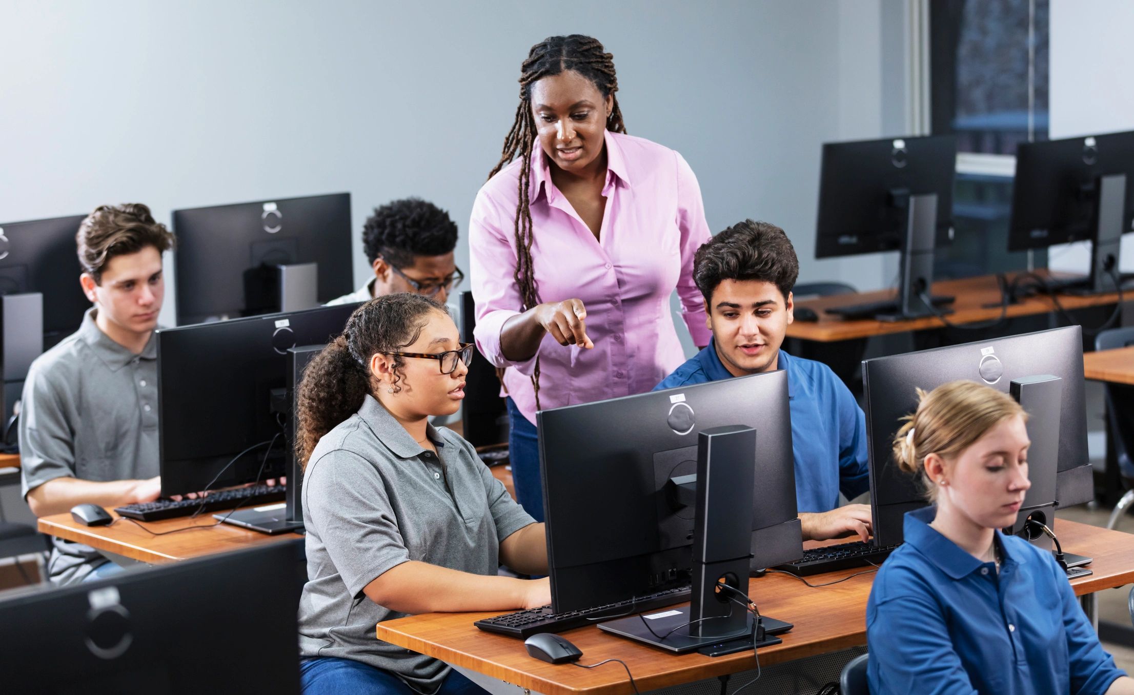Teacher helping students in a computer lab